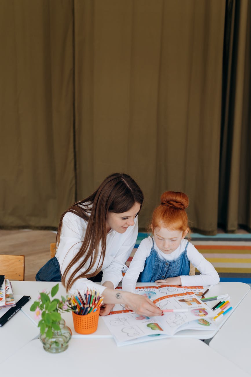 a woman and a girl coloring a book