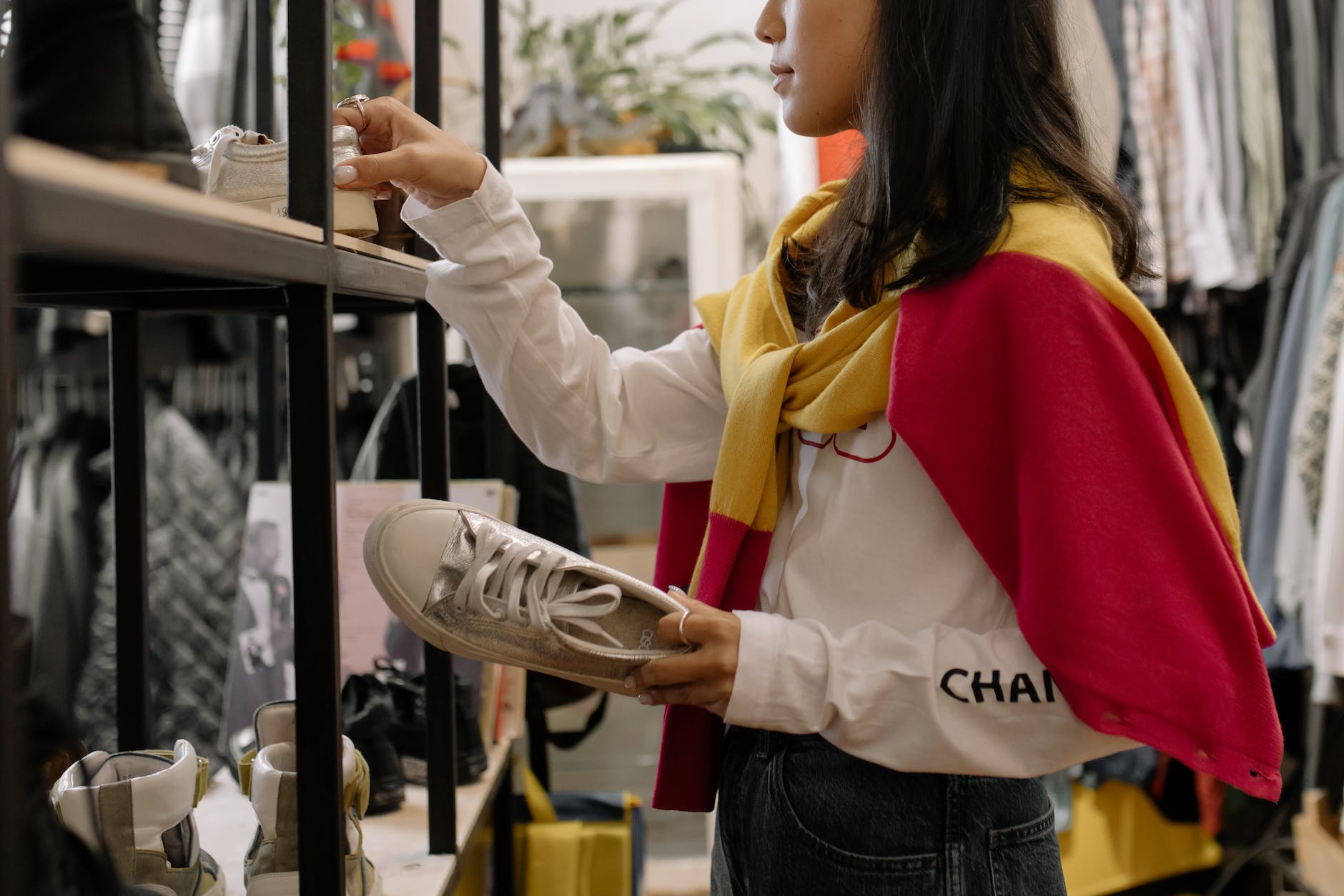 woman in white long sleeve shirt and blue denim jeans holding white shoes