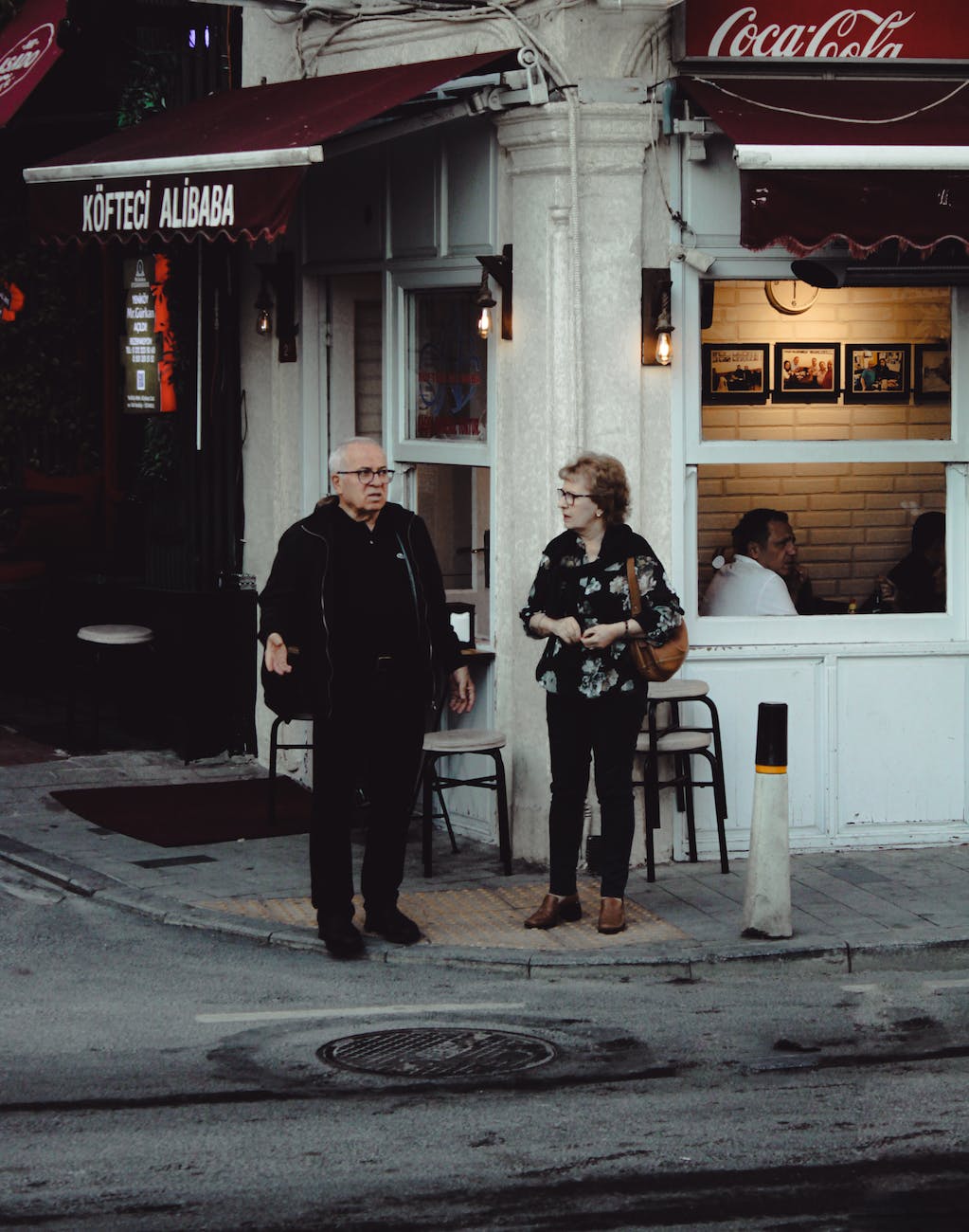 an elderly man and woman having conversation while standing on the street